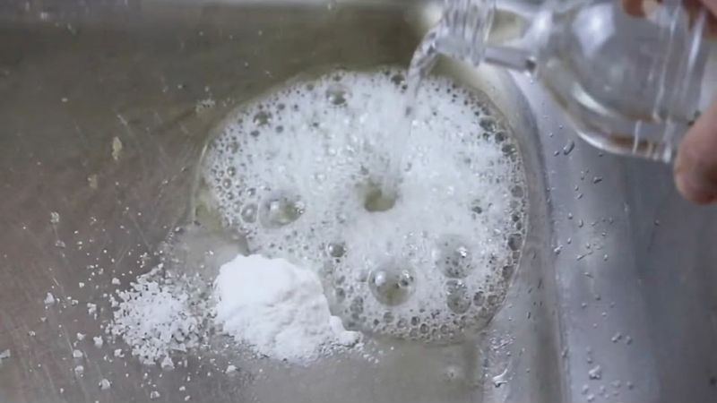 Thông bồn rửa bát bằng muối đúng cách từ chuyên gia 2026 3 Phản ứng sủi bọt CO2 khi kết hợp muối, baking soda và giấm trắng tạo áp lực đẩy lùi mảng bám tắc nghẽn.